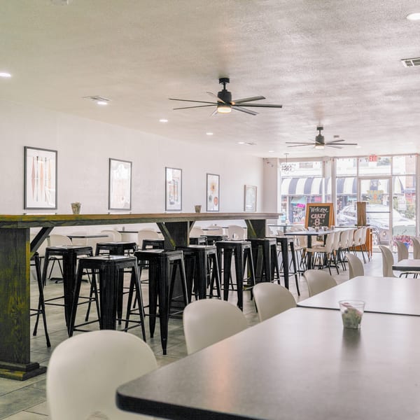 Spacious, brightly lit restaurant interior with various seating arrangements, including high-top tables and standard dining tables.