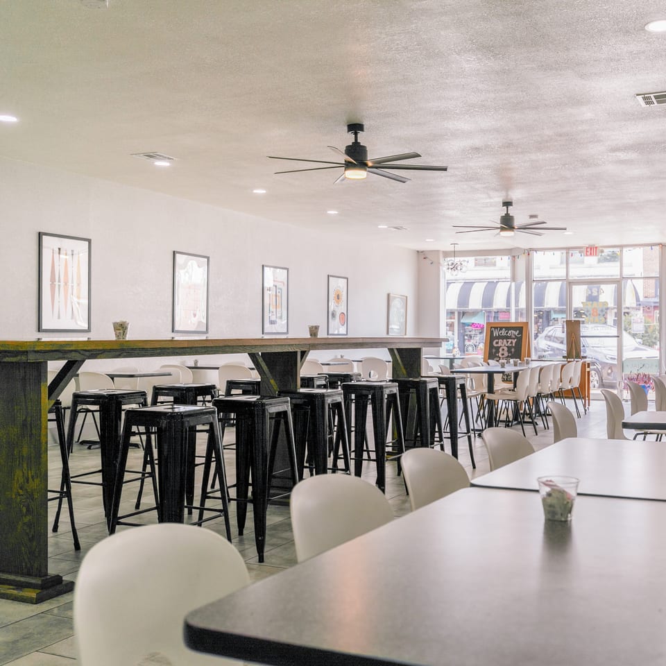 Spacious, brightly lit restaurant interior with various seating arrangements, including high-top tables and standard dining tables.