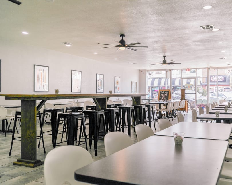 Spacious, brightly lit restaurant interior with various seating arrangements, including high-top tables and standard dining tables.